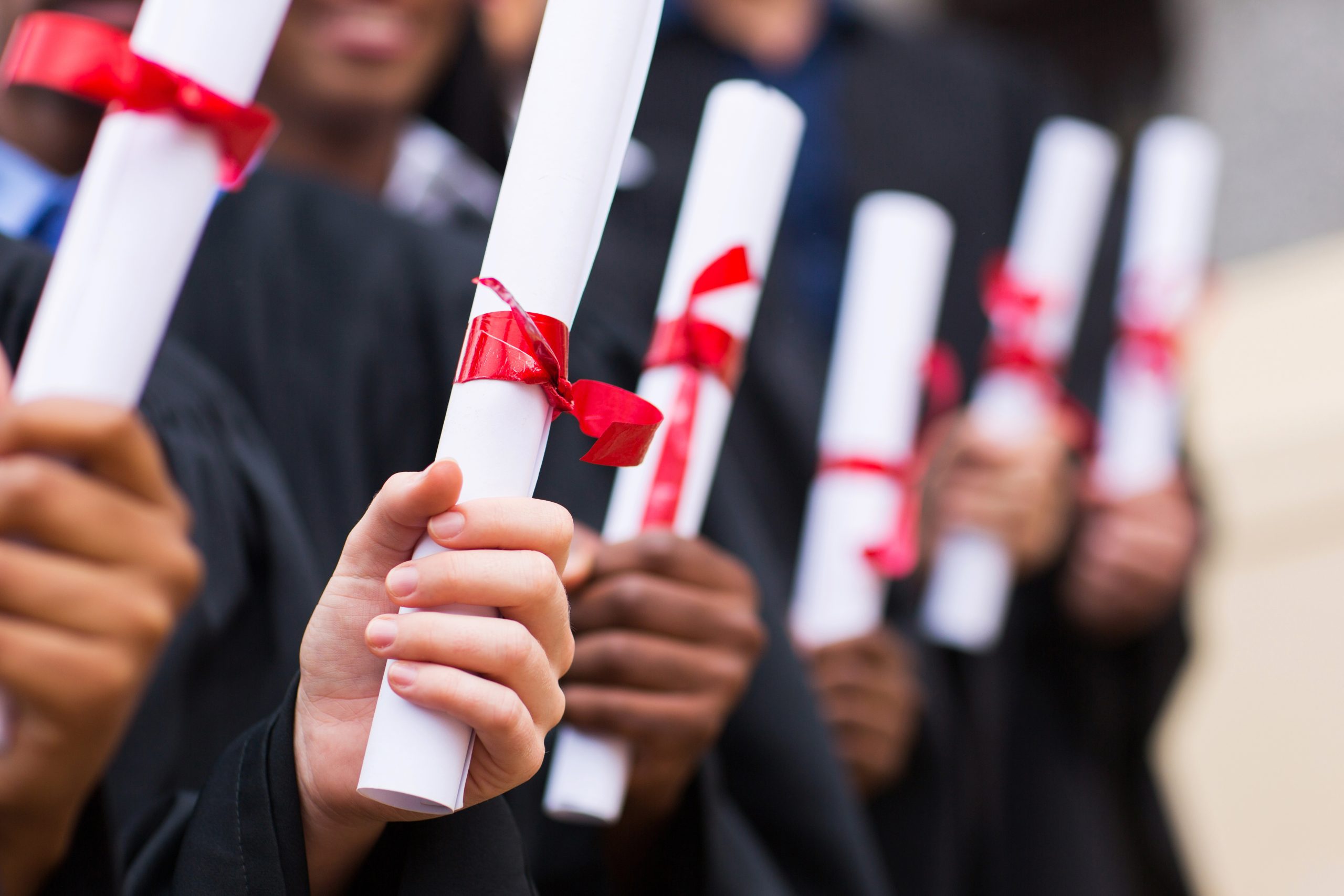 Several hands holding diplomas